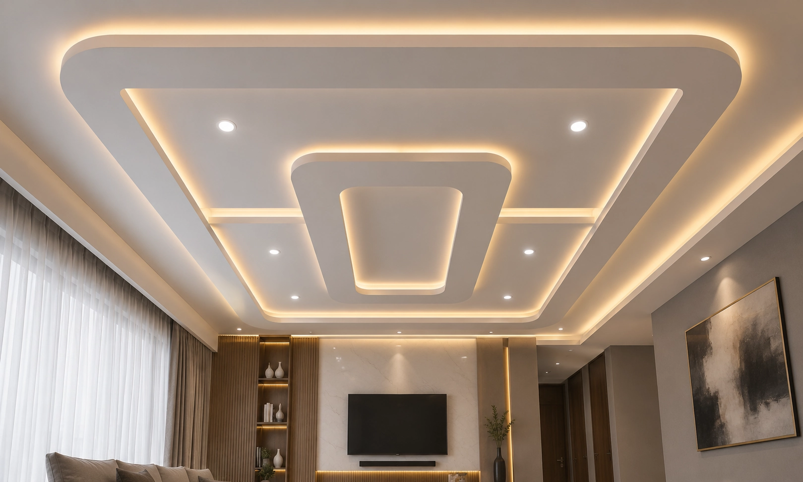 Modern layered gypsum false ceiling with recessed LED cove lighting designed by False Ceiling Interior Designers in Trivandrum for a contemporary living room.