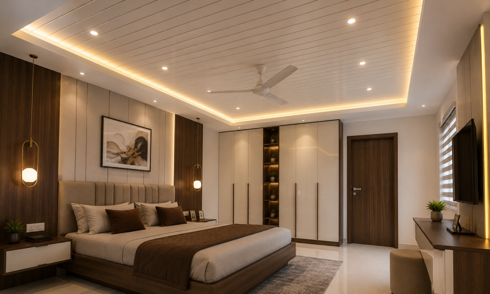 Modern bedroom with a white PVC false ceiling, warm LED cove lighting, recessed spotlights, and ceiling fan designed by False Ceiling Interior Designers in Trivandrum.